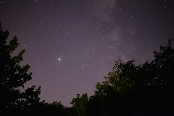 Planets Jupiter and Saturn on summer night sky with milky way galaxy shining trough millions of...