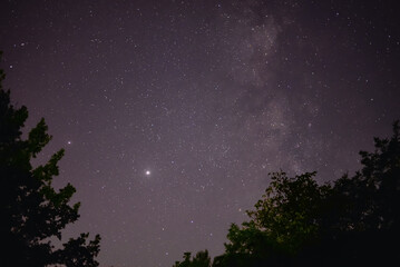 Planets Jupiter and Saturn on summer night sky with milky way galaxy shining trough millions of...