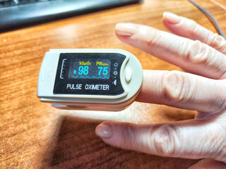 Close up of a hand with a pulse oximeter on the finger.
