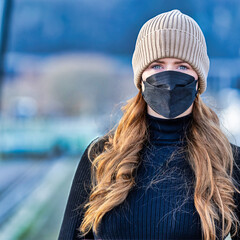 Woman with long red hair and a hat wears an FFP 2 protective mask.