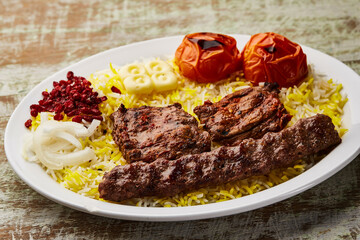Beef Sultani with andana kabab, beef tikka and mandi biryani rice, tomato and onion served in dish isolated on table top view of arabic food