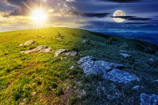 mountain landscape with stones among the grass on top of the hillside beneath a sky with sun and moon at twilight. day and night time change concept. mysterious countryside scenery in morning light