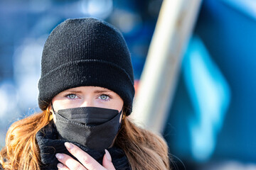 Woman with long red hair and a hat wears an FFP 2 protective mask.