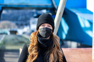 Woman with long red hair and a hat wears an FFP 2 protective mask.