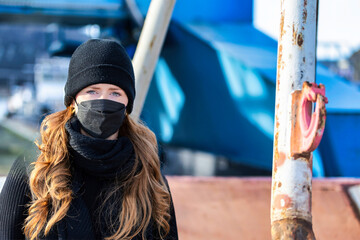 Woman with long red hair and a hat wears an FFP 2 protective mask.