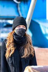 Woman with long red hair and a hat wears an FFP 2 protective mask.