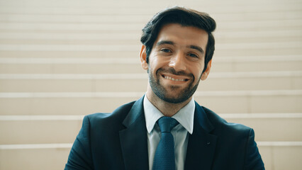 Portrait of smiling business man looking at camera while standing at stairs. Closeup of successful...