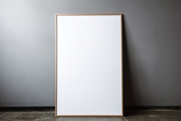 Mockup of an empty poster frame on the floor against grey wall. Minimalist Frame mockup