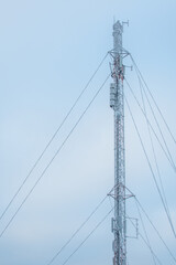 Tall frosty telecommunications tower against a partly cloudy sky - blue and white background