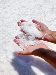 Womans hands with salt in her hands against the backdrop of salt lake.