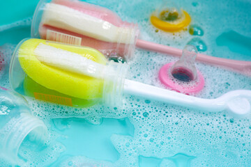 Wash baby bottles in plastic blue basin