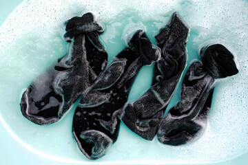 Dirty socks soaked in water, dissolving detergent in basin.