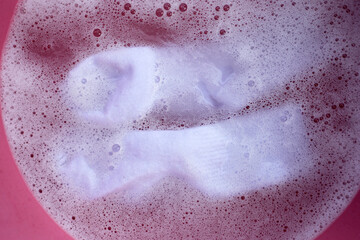 Dirty socks soaked in water, dissolving detergent in basin.