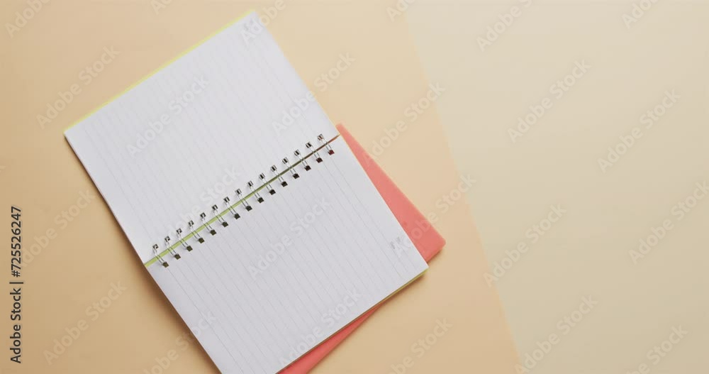 Poster overhead view of open notebook with pink marker with copy space on beige background, in slow motion