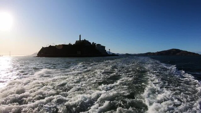 Sailing at Alcatraz prison island in San Francisco, California, USA at sunset with view of Golden Gate bridge at background