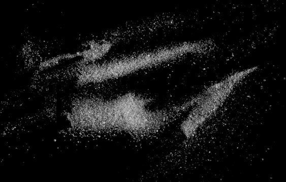White crystal sugar scattered isolated on black background and texture, top view

