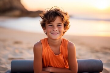 Portrait of cute little boy doing yoga on the beach at sunset