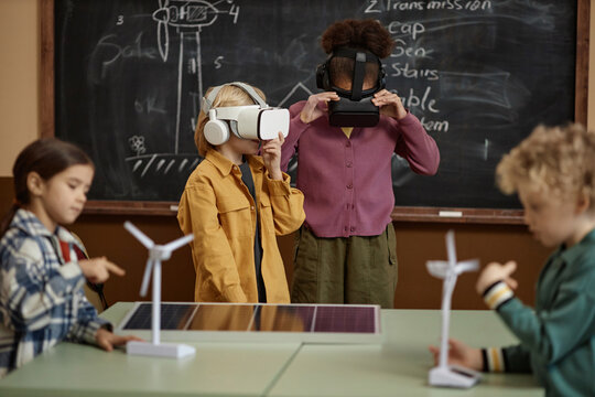 Portrait of two school children wearing VR headsets in class and learning about renewable energy