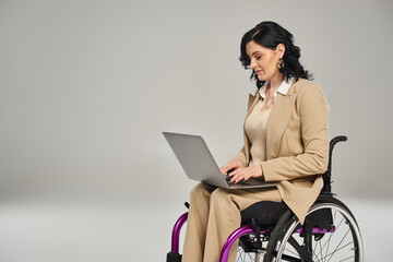beautiful confident disabled woman in wheelchair wearing pastel suit and working on her laptop