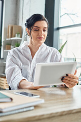 beautiful disabled businesswoman in trendy attire in wheelchair working on her tablet in office