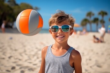 Portrait of a smiling boy playing with a volleyball on the beach