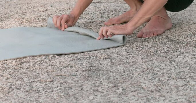 Person rolls up yoga mat after meditation close-up Yoga mat companion in nature's meditation. Yoga mat symbolizing commitment mental health Ritual embodies serenity and journey towards inner calm.