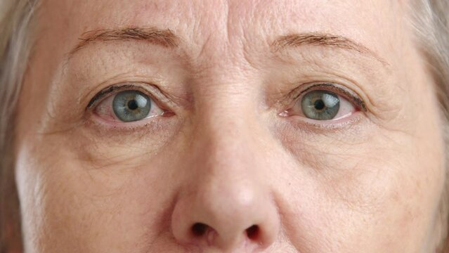 An intimate close-up of an elderly woman's eyes and nose, the photo captures a deep gaze full of experience and stories, with a sharp focus on the details of aging. Camera 8K RAW. 