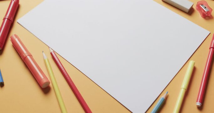 Close up of blank sheet of paper with school stationery on beige background, in slow motion