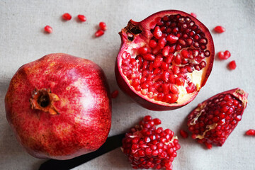 A cut pomegranate next to a whole one on a gray background