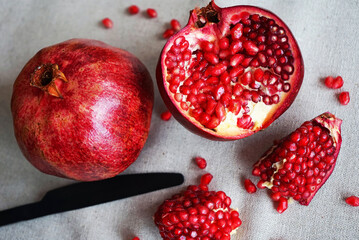 A cut pomegranate next to a whole one on a gray background
