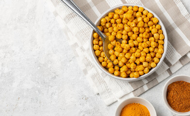 Сrispy roasted chickpeas with spices curry powder and turmeric in a light bowls top view with copy space