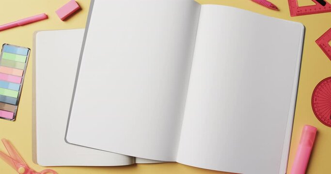 Overhead view of open notebooks with school stationery on beige background, in slow motion