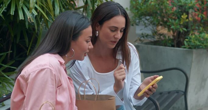 Female friends sitting on bench engaged conversation phones showcasing women's friendship. Women's friendship evident shared moments laughter Women's friendship symbol trust positive vibes.