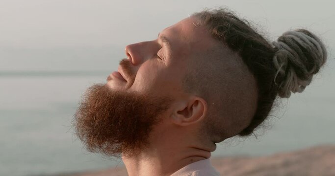 On sea beach man with beard finds inner freedom through meditation head in close up. Inner freedom core of mental well-being Fostering healthy confident life Inner freedom merges with nature beauty.