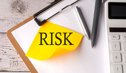 RISK word on a yellow sticky with calculator, pen and clipboard