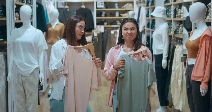 Women friends clothing store trying on fashionable outfits discussing choices. Women friends enjoy shopping reflecting happiness modern lifestyle Women friends joy discovering beautiful items.