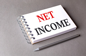 NET INCOME word on notebook on grey background