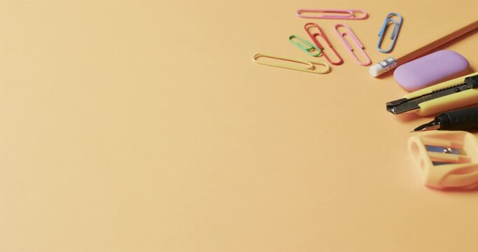 Close up of colourful school stationery with copy space on beige background, in slow motion