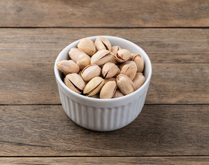 Salted roasted pistachios on a bowl over wooden table