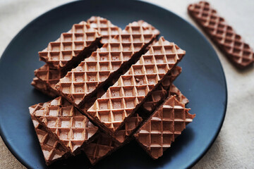 Chocolate wafers on a black plate on a gray background