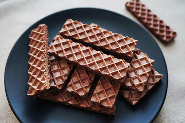 Chocolate wafers on a black plate on a gray background
