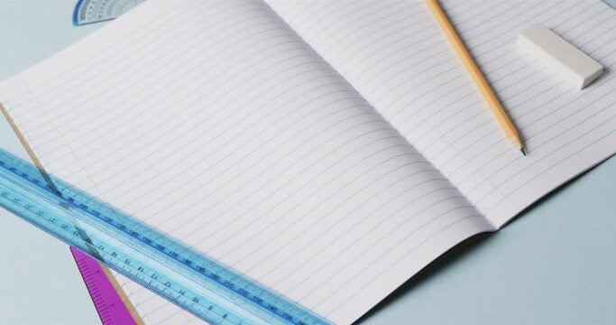 Close up of open notebook with school stationery on blue background, in slow motion