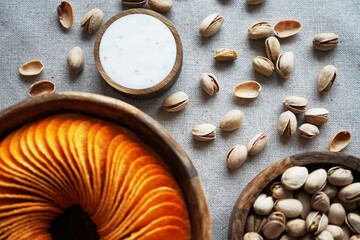 Potato chips and pistachios in wooden bowls next to sauce on gray background