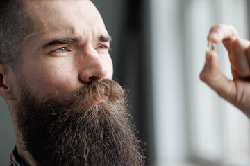 Fototapeta premium Portrait brutal guy holding a pill in his hand.