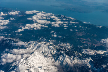 Obraz premium view from the airplane window to mountains clouds and blue sky