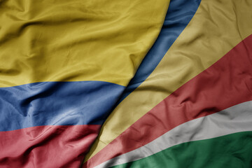 big waving national colorful flag of seychelles and national flag of colombia .