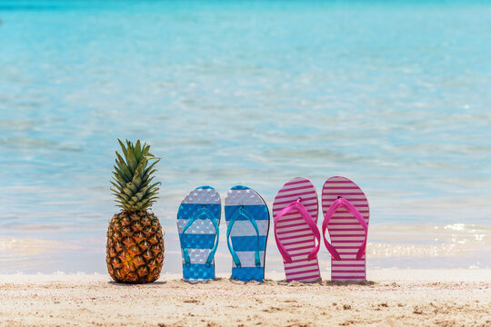 Summer background with pineapple and slippers on a tropical beach.