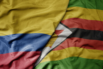 big waving national colorful flag of zimbabwe and national flag of colombia .