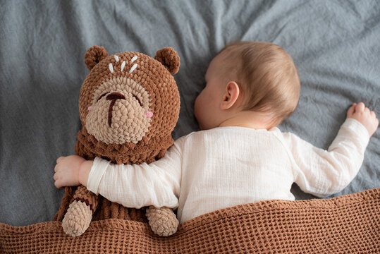 Little baby boy with toy in bed, handmade pajama bag, sleepwear organizer