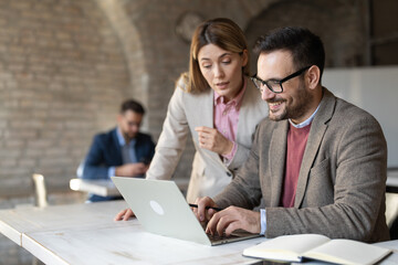 Obraz premium Businesswoman and businessman working together at laptop